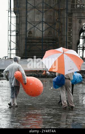 Mumbai, Maharashtra/Indien - 11. Juni 2008: Der Blick auf die beiden Männer, die mit einem Schirm und einem Ballon während des Regens auf der Straße stehen. Stockfoto