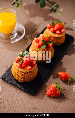 Gourmet-Tartlets mit Reifen Erdbeeren und Minzblättern, serviert mit einem Glas Orangensaft Stockfoto