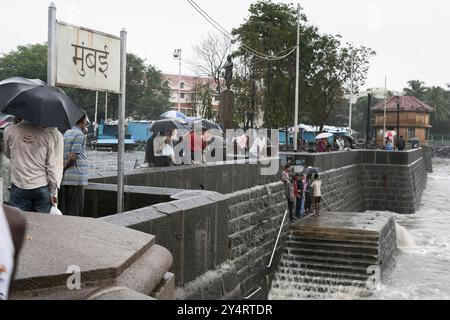 Mumbai, Maharashtra / Indien - 11. Juni 2008: Touristen in der Nähe des Torres of India beobachten das Spritzen des Meerwassers mit der Mauer während des Monsunregens. Stockfoto