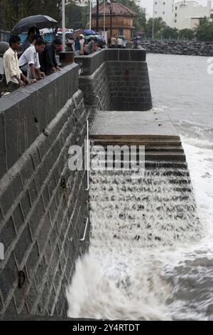 Mumbai, Maharashtra / Indien - 11. Juni 2008: Touristen in der Nähe des Torres of India beobachten das Spritzen des Meerwassers mit der Mauer während des Monsunregens. Stockfoto