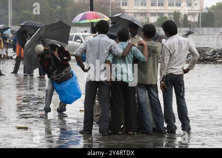 Mumbai, Maharashtra / Indien - 11. Juni 2008: Ein Fotograf fotografiert eine Gruppe junger Männer in der Nähe des Torres of India während des Regens. Stockfoto