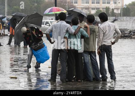 Mumbai, Maharashtra / Indien - 11. Juni 2008: Ein Straßenfotograf, der während des Regens im Monsun ein Foto einer Gruppe junger Reisende macht. Stockfoto