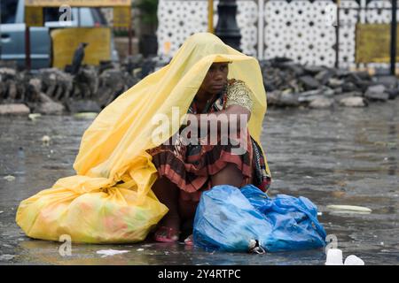 Mumbai, Maharashtra / Indien - 11. Juni 2008: Eine Frau, die während des Regens in der Monsunsaison auf der Straße sitzt. Stockfoto