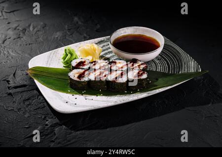 Sushi-Brötchen mit Belag, serviert mit Sojasauce, Ingwer und Wasabi auf einem strukturierten Teller Stockfoto