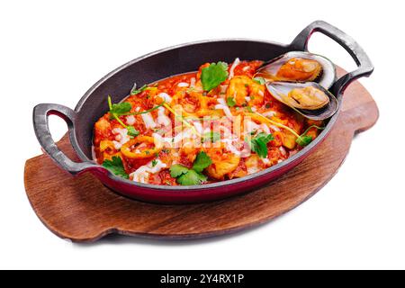 Appetitliche Meeresfrüchte-Mischung mit Kräutern in einer gusseisernen Pfanne auf einem Holzbrett isoliert auf weiß Stockfoto