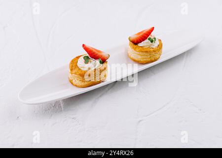 Köstliche Blätterteigdesserts mit Sahne und frischen Erdbeeren auf einem eleganten weißen Teller Stockfoto