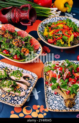 mediterrane Gerichte auf einer gemusterten Tischdecke mit frischem Gemüse und Einrichtung Stockfoto