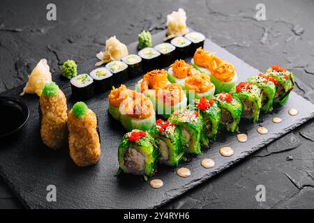 Auswahl an frischem Sushi und Brötchen, elegant auf einem dunklen Schieferbrett präsentiert, perfekt für Menüs oder Food Blogs Stockfoto