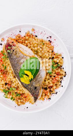 Blick von oben auf ein gegrilltes Lachsfilet, serviert mit gewürztem Couscous, garniert mit Kräutern Stockfoto