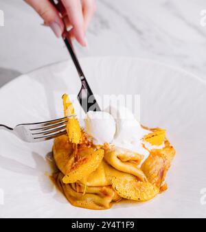 Köstliche Pfannkuchen Dessert Eiskugel mit Orangenschale garniert, Gabel in Aktion Stockfoto