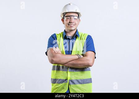 Porträt eines lächelnden lateinischen Ingenieurs mit gekreuzten Armen. Junger latein-Ingenieur mit Helm und Weste isoliert Stockfoto
