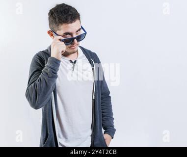 Gutaussehender Kerl, der seine Brille senkt und in die Kamera schaut. Attraktiver junger Mann mit Brille, der isoliert in die Kamera schaut Stockfoto