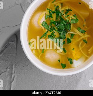 Blick von oben auf eine gemütliche Schüssel mit Hühnernudelsuppe, garniert mit Petersilie auf einer strukturierten Oberfläche Stockfoto