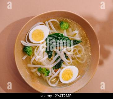 Eine warme Schüssel Udon-Nudelsuppe mit halbem Ei und frischem Gemüse Stockfoto