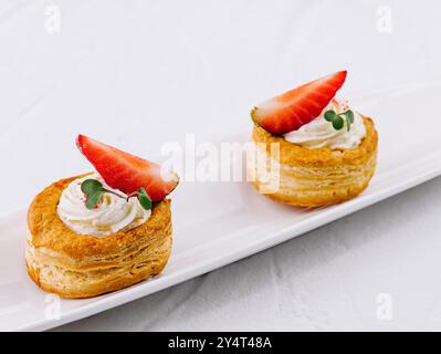 Köstliche Blätterteigdesserts mit Sahne und frischen Erdbeeren auf einem eleganten weißen Teller Stockfoto