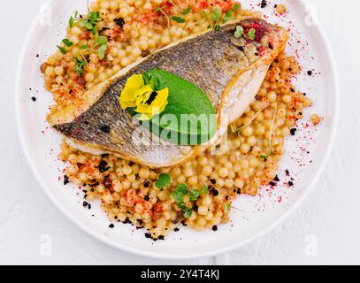 Blick von oben auf ein gegrilltes Lachsfilet, serviert mit gewürztem Couscous, garniert mit Kräutern Stockfoto