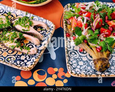 mediterrane Gerichte auf einer gemusterten Tischdecke mit frischem Gemüse und Einrichtung Stockfoto