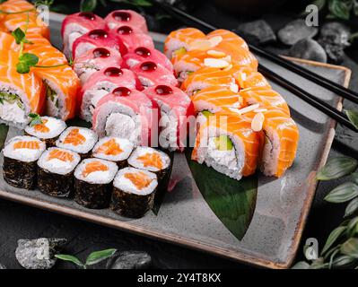 Elegantes Sushi-Set mit verschiedenen Brötchen und Sashimi auf einem modernen Teller mit Beilagen Stockfoto