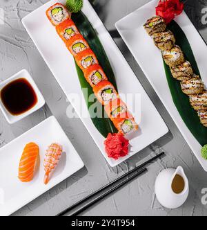 Exquisite Sushi-Auswahl, kunstvoll auf modernen Tellern mit tropischem Blattdekor Stockfoto