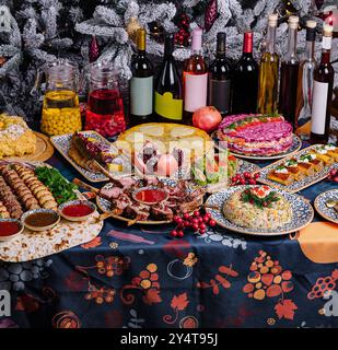 Üppiger Feiertagstisch mit einer Auswahl an Gerichten vor einem wunderschön dekorierten weihnachtsbaum Stockfoto