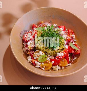 Frischer Tomaten-Couscous-Salat mit Feta und Kräutern, wunderschön präsentiert in einer Keramikschale Stockfoto