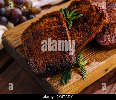 Ein Schuss frisch gebackener Brownies mit frischen Kräutern, serviert mit Trauben auf einem rustikalen Brett Stockfoto