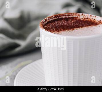 Gemütliche Szene mit einer weißen Tasse Cappuccino mit Schaumkunst und Grün Stockfoto
