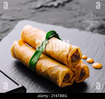 Drei köstliche frische Frühlingsbrötchen mit Schnittlauch auf einem Schiefer, serviert mit Dippsoße Stockfoto