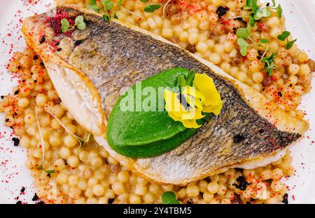 Blick von oben auf ein gegrilltes Lachsfilet, serviert mit gewürztem Couscous, garniert mit Kräutern Stockfoto