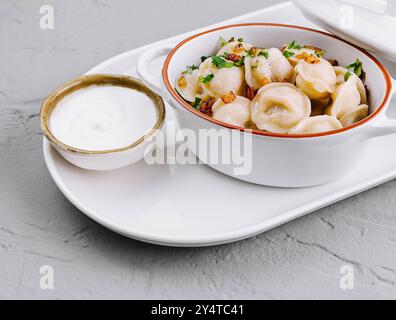 Köstliche traditionelle Knödel garniert mit frischer Petersilie in einem stilvollen Keramiktopf, servierfertig Stockfoto