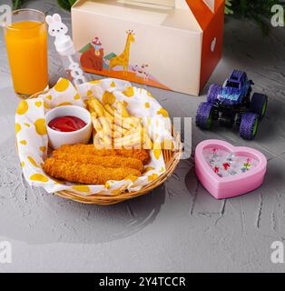 Bunte Kindermahlzeit mit Hühnchen, Pommes Frites und Saft, begleitet von einem kleinen Spielzeugauto Stockfoto