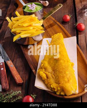 Appetitlicher traditioneller Fisch und Pommes frites serviert mit Erbsen, Knoblauch von oben Stockfoto