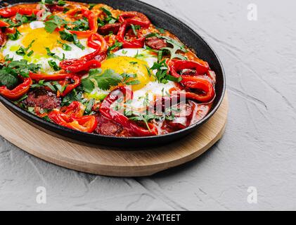 Traditionelle Shakshuka mit Eiern, Tomaten und Paprika garniert mit Petersilie, serviert in einer gusseisernen Pfanne Stockfoto