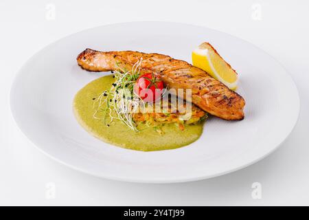 Köstlich gegrilltes Lachsfilet, serviert mit einer lebendigen grünen Sauce, Zitrone und frischer Beilage Stockfoto