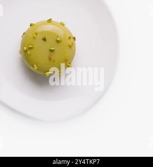 Einzelner Pistazien-Macaron, verziert mit Nüssen, isoliert auf weißem Hintergrund Stockfoto