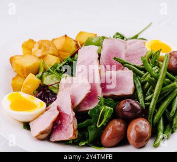 Lebendiger und nahrhafter Nicoise-Salat mit gebratenem Thunfisch, Gemüse, Eiern und Kartoffeln Stockfoto