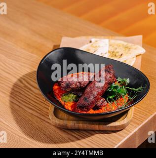 Elegantes Restaurant mit gegrillten Würstchen mit frischen Beilagen und Fladenbrot Stockfoto