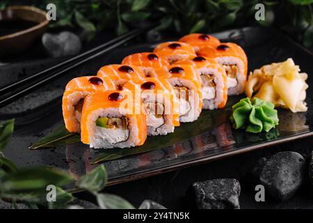 Philadelphia Sushi-Brötchen mit Lachs und Frischkäse auf schwarzem Teller serviert Stockfoto