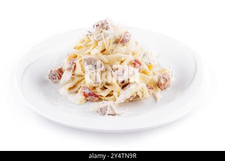 Teller mit Pasta Carbonara mit Speck und Pilzen auf weißem Hintergrund Stockfoto