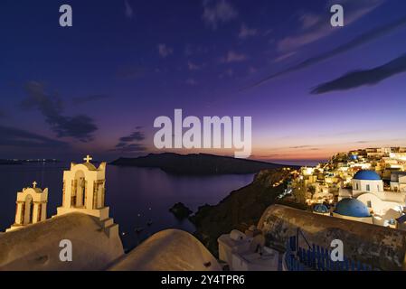 Nächtlicher Blick auf die blauen Kuppelkirchen und den Glockenturm mit Blick auf die Ägäis in Oia, Santorin, Griechenland, Europa Stockfoto