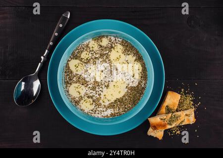 Türkische yayla-Suppe mit getrockneter Minze und geschmolzener Butter in einer blauen Schüssel, serviert mit traditionellem Brot Stockfoto