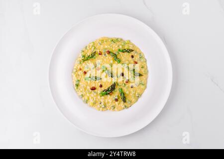 Köstliches Risotto mit Spargel und knusprigen Pancetta-Stücken, serviert auf einem weißen Teller Stockfoto