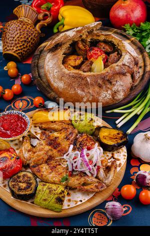 Georgianische Küche mit gegrilltem Huhn, Gemüse und gebackenem Brot auf dem Tisch mit Soße, Kräutern und Gewürzen Stockfoto