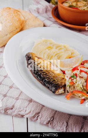 Gegrillte Makrele serviert mit Kartoffelpüree und Salat auf weißem Teller mit Zitrone, gesundes Essen Stockfoto