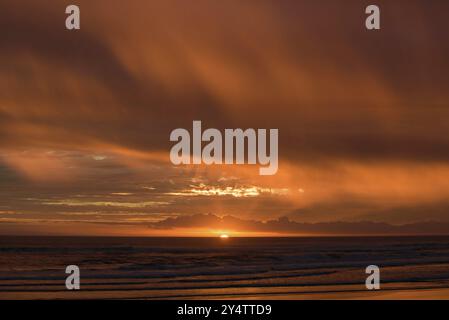 Muriwai Beach bei Sonnenuntergang mit bunten Wolken, Neuseeland, Ozeanien Stockfoto