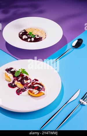 Köstliches Frühstück mit Pfannkuchen, Marmelade, Haferbrei, Beeren und Nüssen auf einem bunten Hintergrund mit Besteck Stockfoto