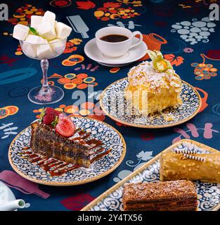 Ein Stück Mohnkuchen, ein Stück napoleon-Kuchen und zwei weitere Desserts werden auf einem Tisch mit einer Tasse Kaffee serviert Stockfoto