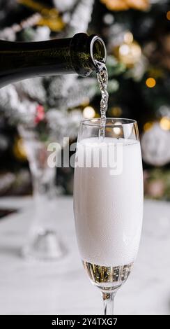 Nahaufnahme von Sekt, der in ein Flötenglas mit festlichem Hintergrund gegossen wird Stockfoto