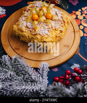 Traditioneller napoleon-Kuchen, geschmückt mit Physalis-Früchten, mit Zucker bestreut, auf einer lebendigen Tischdecke Stockfoto