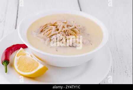 Türkische Kuttelsuppe mit Zitrone und rotem Pfeffer auf einem weißen Holztisch Stockfoto